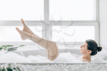 Female person heels sticking out of the bath with foam. Relaxation, health and body care in bathroom, spa