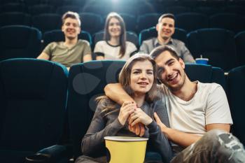 Young smiling man hugs his woman in cinema. Showtime, entertainment industry, movie watching