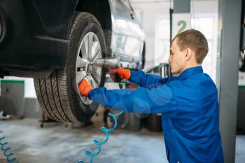 Mechanic unscrews the wheel with a pneumatic wrench. Car service, automobile repair, vehicle maintenance