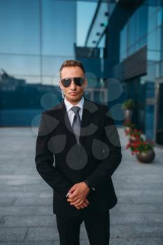 Male bodyguard in suit and sunglasses outdoors. Guarding is a risky profession. Professional guard, politician persons and businesspeople safeguard, safe control