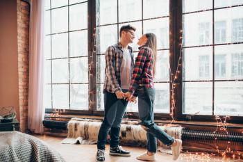 Happy young couple hugs together against large window from floor. Man and woman embrace, romantic relationship