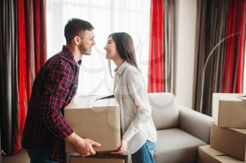 Young couple arrange carton boxes on a room, moving to new house. Relocation to apartment with packaging