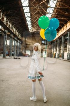 Pretty anime style blonde lady with colorful air balloons. Cosplay fashion, asian culture, doll in dress, cute woman with makeup in the factory shop