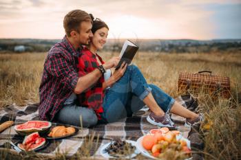 Love couple reads book together, picnic on the grass. Romantic junket, man and woman on outdoor dinner,  happy family weekend