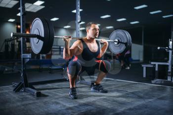 Muscular powerlifter doing squats with barbell in gym. Weightlifting workout, powerlifting training, lifter in sport club