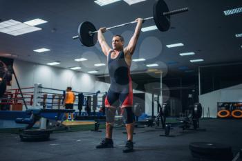 Strong male powerlifter doing deadlift a barbell in gym. Weightlifting workout, lifting training, athlete works with weight in the sport club