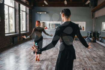 Man and woman on ballrom dance training in class. Female and male partners on professional pair dancing in studio