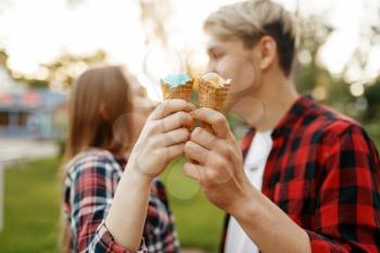 Love couple with ice cream in summer park, romantic youth. Young boyfriend and girl leisures with ice-cream together outdoor
