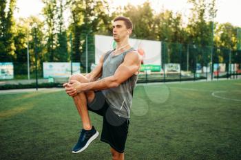 Man in sportswear prepares for outdoor fitness workout. Strong sportsman on training in park