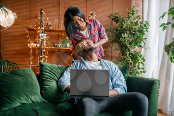 Black couple with laptop having fun on sofa at home. Happy african love couple leisures in their house, cheerful family relaxing at home