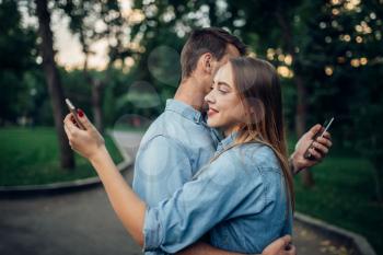 Phone addiction, addict couple hugs and using gadgets in summer park, social addicted people