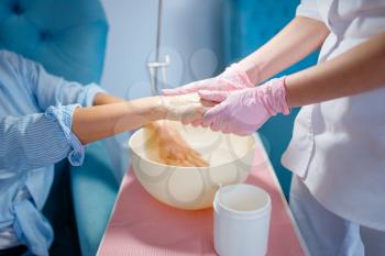 Beautician salon, hands massage procedure. Nail care treatment for female client in beauty shop, doctor in gloves works with customer before manicure, woman at the manicurist
