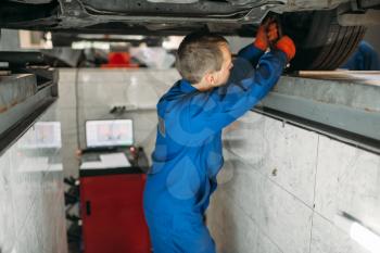 Mechanic adjusts the wheel angles on stand in auto-service. Computer diagnostic of car suspension, collapse of convergence