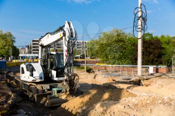 Construction site on the street of the old european city. Excavator on sand pile in downtown, building engineering