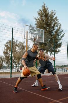 Two basketball players set up a match on outdoor court, active leisure. Male athletes in sportswear play the game on streetball training