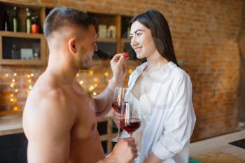 Sensual couple spend romantic dinner on the kitchen together. Man and woman preparing breakfast at home, food preparation with elements of eroticism