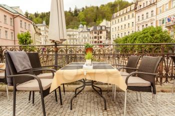 Cosy outdoor cafe with rattan furniture and view on river, Karlovy Vary, Czech Republic, Europe. Old european town, famous place for travel