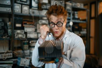 Strange engineer examines the cooling radiator, test in laboratory. Electrical testing tools on background. Lab equipment, engineering workshop