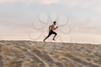 Male athlete on running workout in desert at sunny day. Strong motivation in sport, strength outdoor training
