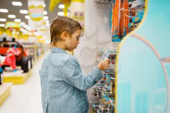 Little boy buying bicycle in kids store, side view. Son choosing toys in supermarket, family shopping, young customer