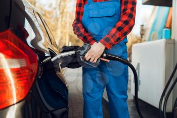 Male worker in uniform fuels car on gas station, fuel filling. Petrol fueling, gasoline or diesel refuel service