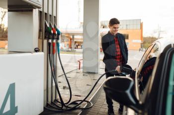 Man with gun fuels vehicle on gas station, fuel filling. Petrol fueling, gasoline or diesel refuel service