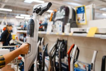 Male person hand holds vacuum cleaner in electronics store. Man buying home electrical appliances in market