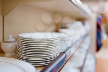 White plates on the shelf closeup, houseware store, nobody. Home goods in market, kitchenware supply shop products