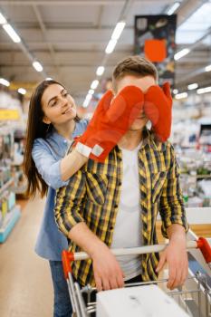 Young playful couple, shopping in houseware store. Man and woman buying home goods in market, family in kitchenware supply shop