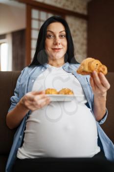 Pregnant woman with belly eating sweets. Pregnancy, gluttony in prenatal period. Expectant mom resting at home