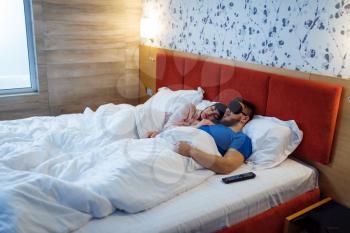 Love couple sleeping in eye covers in bed at home, healthy comfort sleep. Harmonious relationship in young family. Man and woman resting together in their house, carefree weekend