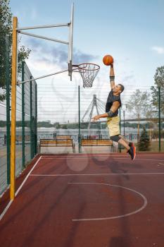 Basketball player makes shoot in jump. Male athlete in sportswear scores on streetball training