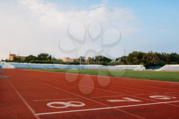 Start line for running on stadium, nobody, front view. Empty treadmill with numbers, injury-proof coating, jogging surface on sport arena