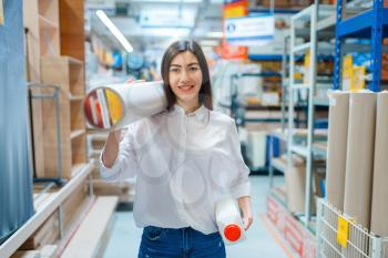 Female consumer buying wallpapers in hardware store. Customer look at the goods in diy shop, shopping in building supermarket