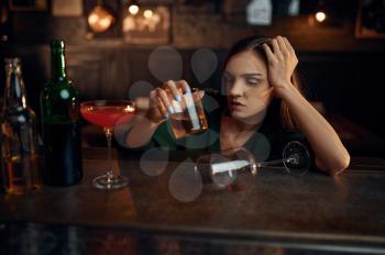 Drunk woman drinks different alcohol at the counter in bar. One female person in pub, human emotions, leisure activities, nightlife