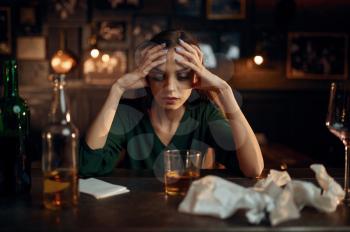 Drunk depressed woman drinks alcohol beverage at the counter in bar. One female person in pub, human emotions, leisure activities, nightlife