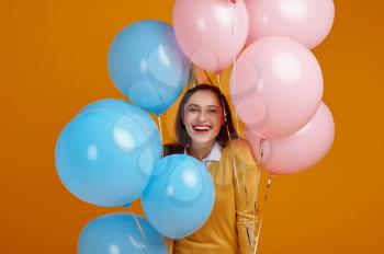 Funny woman in cap, yellow background. Pretty female person got a surprise, event or birthday celebration, balloons