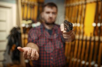 Man aims with new handgun in camera, gun shop. Male person buying pistol for security in weapon store, selfdefence and sport shooting hobby