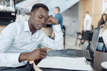 Ebony businessman working on laptop in office. Successful business person at his workplace, black man in formal wear