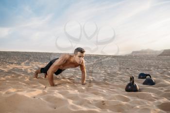 Sportsman doing push-up exercises in desert at sunny day. Strong motivation in sport, strength outdoor training