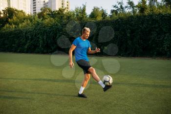 Male soccer player with ball standing on line on the field. Footballer on outdoor stadium, workout before football match