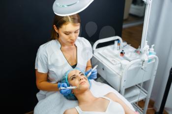 Cosmetician smoothes face of female patient after botox injections. Rejuvenation procedure in beautician salon. Doctor and woman, cosmetic surgery against wrinkles and aging