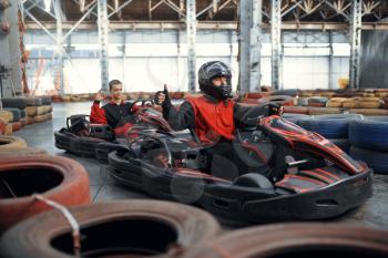 Two kart racers, karting auto sport indoor. Speed race on close go-kart track with tire barrier. Fast vehicle competition, active hobby