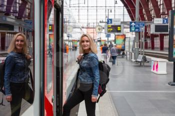 Female tourist with backpack enters the train on railway station platform, travel in Europe. Transportation by european railroads, comfortable tourism and travelling