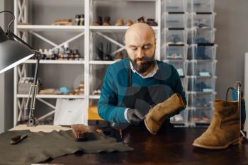 Shoemaker sharpens the shoe sole, footwear repair service. Craftsman skill, shoemaking workshop, cobbler job