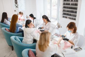 Group of girlfriends relax on manicure procedure in beauty salon. Professional beautician and female customers, nail care in spa studio, fingernail treatment