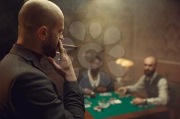 Three poker players sitting at the table in casino. Games of chance addiction, gambling house,