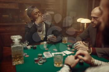 Three poker players sitting at gaming table with green cloth in casino. Games of chance addiction, gambling house. Men leisures with whiskey and cigars,