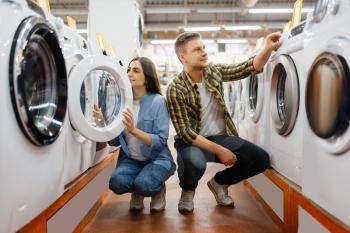 Family couple choosing washing machine in electronics store. Man and woman buying home electrical appliances in market