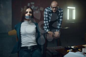 Maniac kidnapper and his victim with taped mouth. Kidnapping is a serious crime, kidnap horror, violence